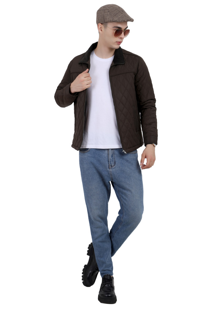 A tilted pose of a man wearing a Dark Olive quilted jacket t with a collar neck, zipper closure and pocket in hand designed for casual winter layering and comfort.